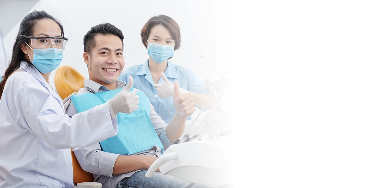 คนไข้รากฟันเทียมยิ้มพร้อมทันตแพทย์และผู้ช่วยทันตแพทย์ The Dent Clinic